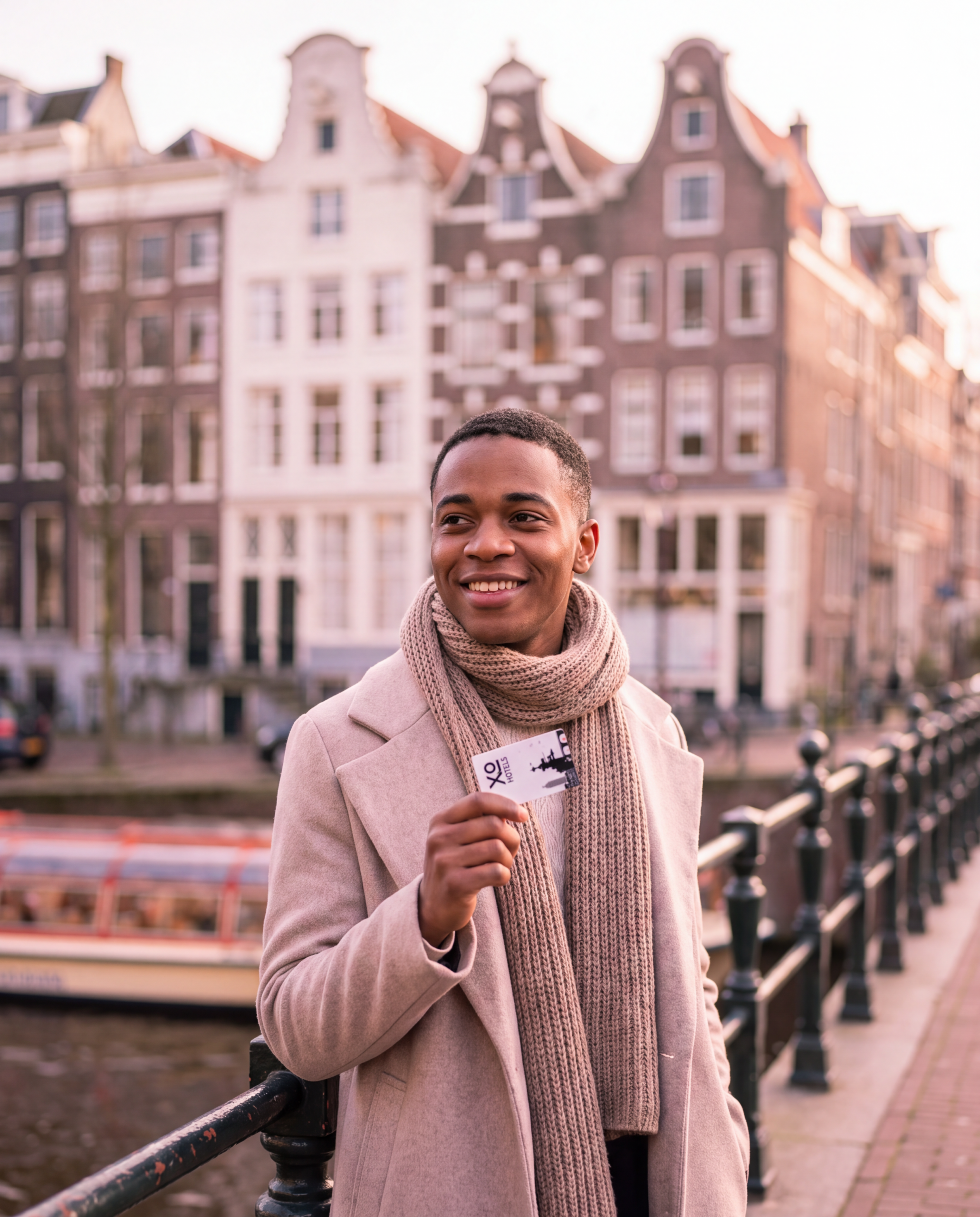 An XO Hotels guest holding their keycard on an Amsterdam canal bridge